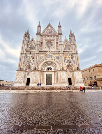 Vista frontale del Duomo di Orvieto che evidenzia lo stile gotico della facciata con le slanciate guglie.